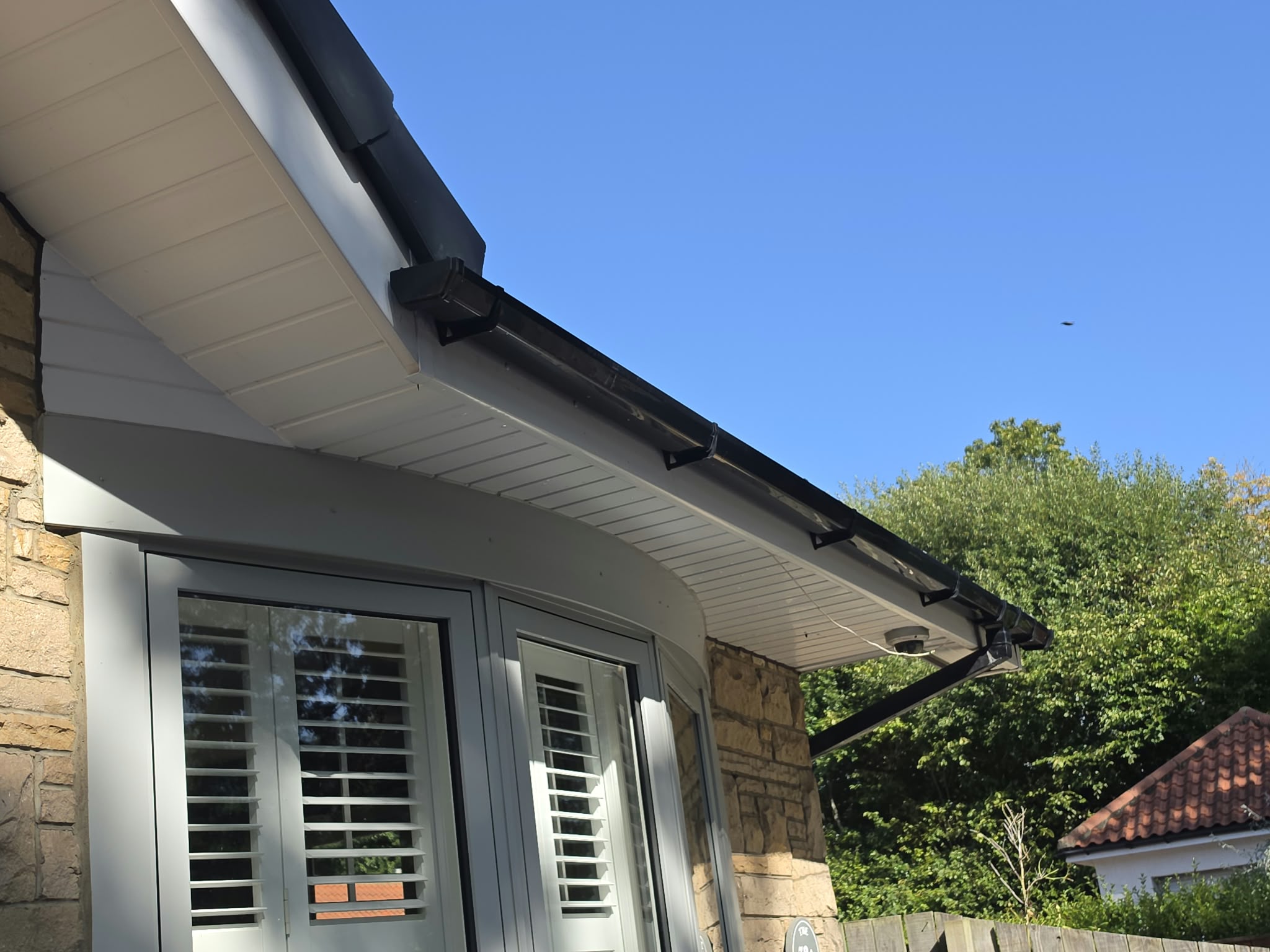 White soffit boards, white fascia and a black external gutter above patio doors