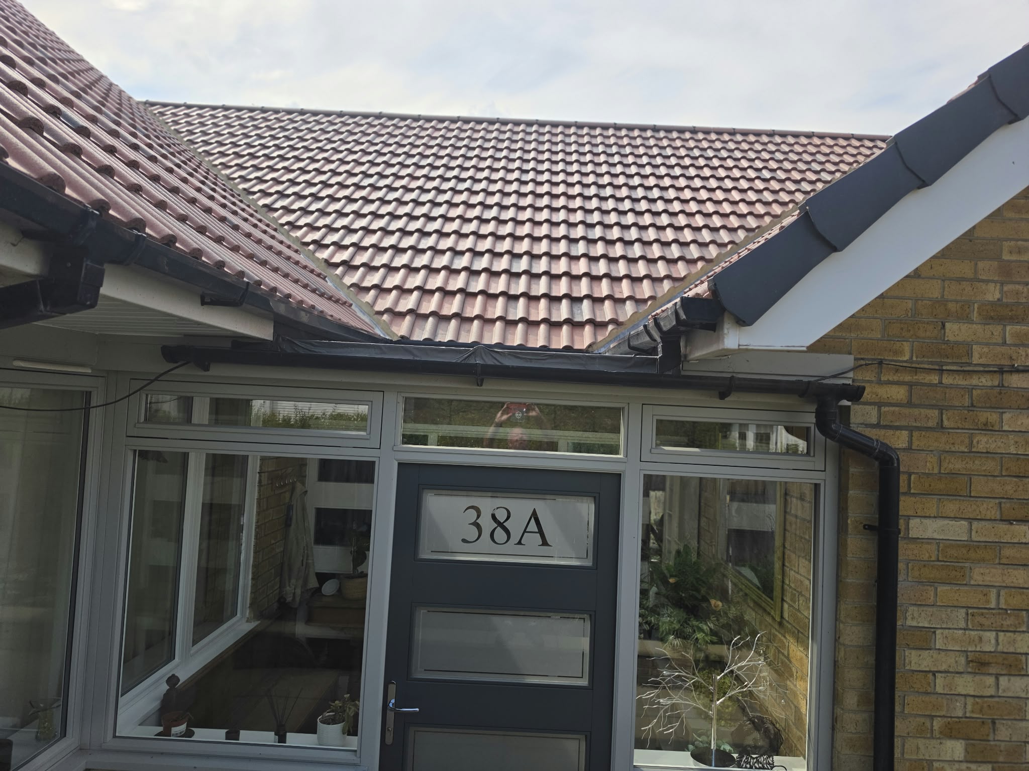 Black external gutter running above a glazed porch and front door