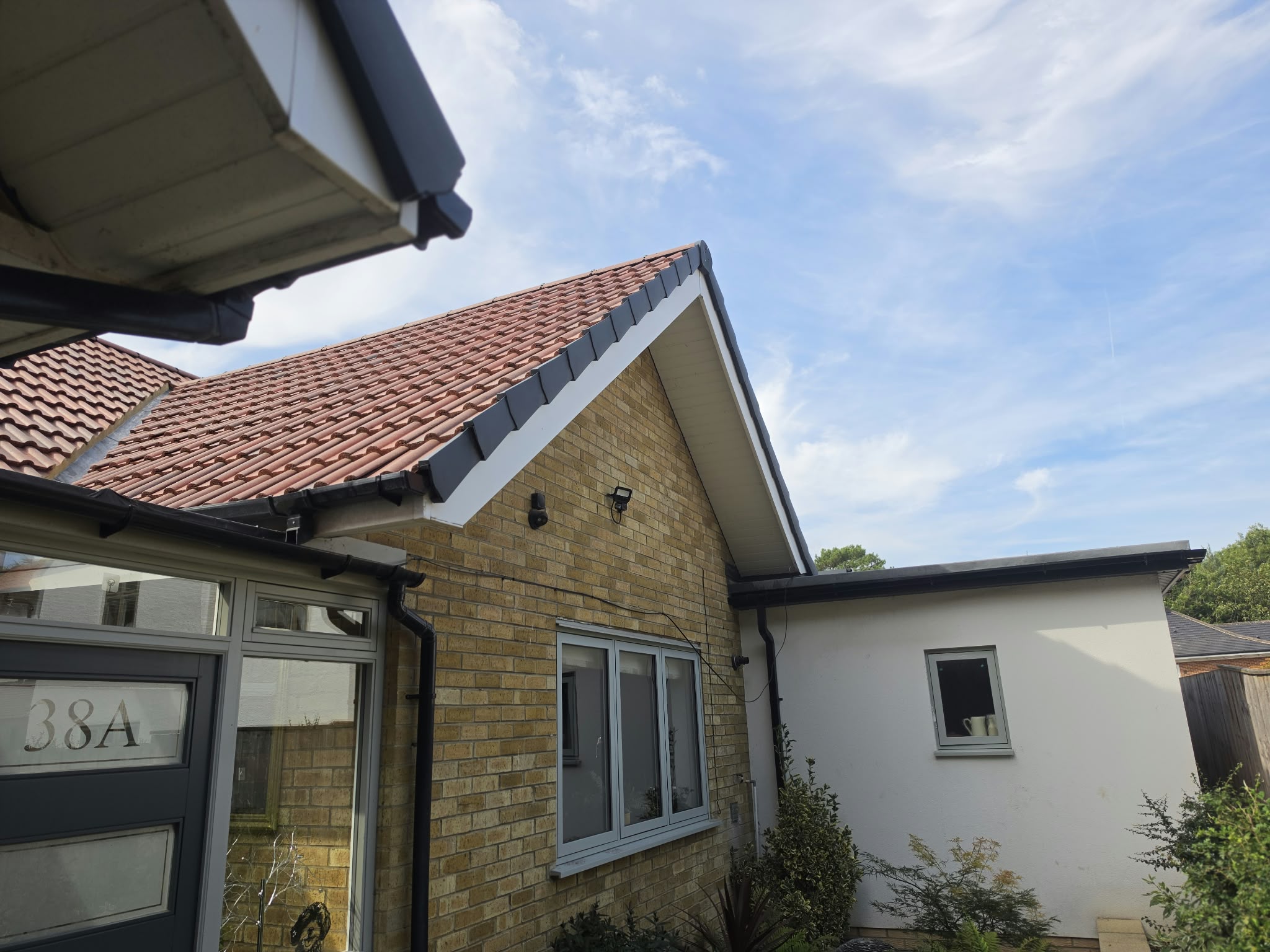 Black gutters and white gable fascia on a brick house