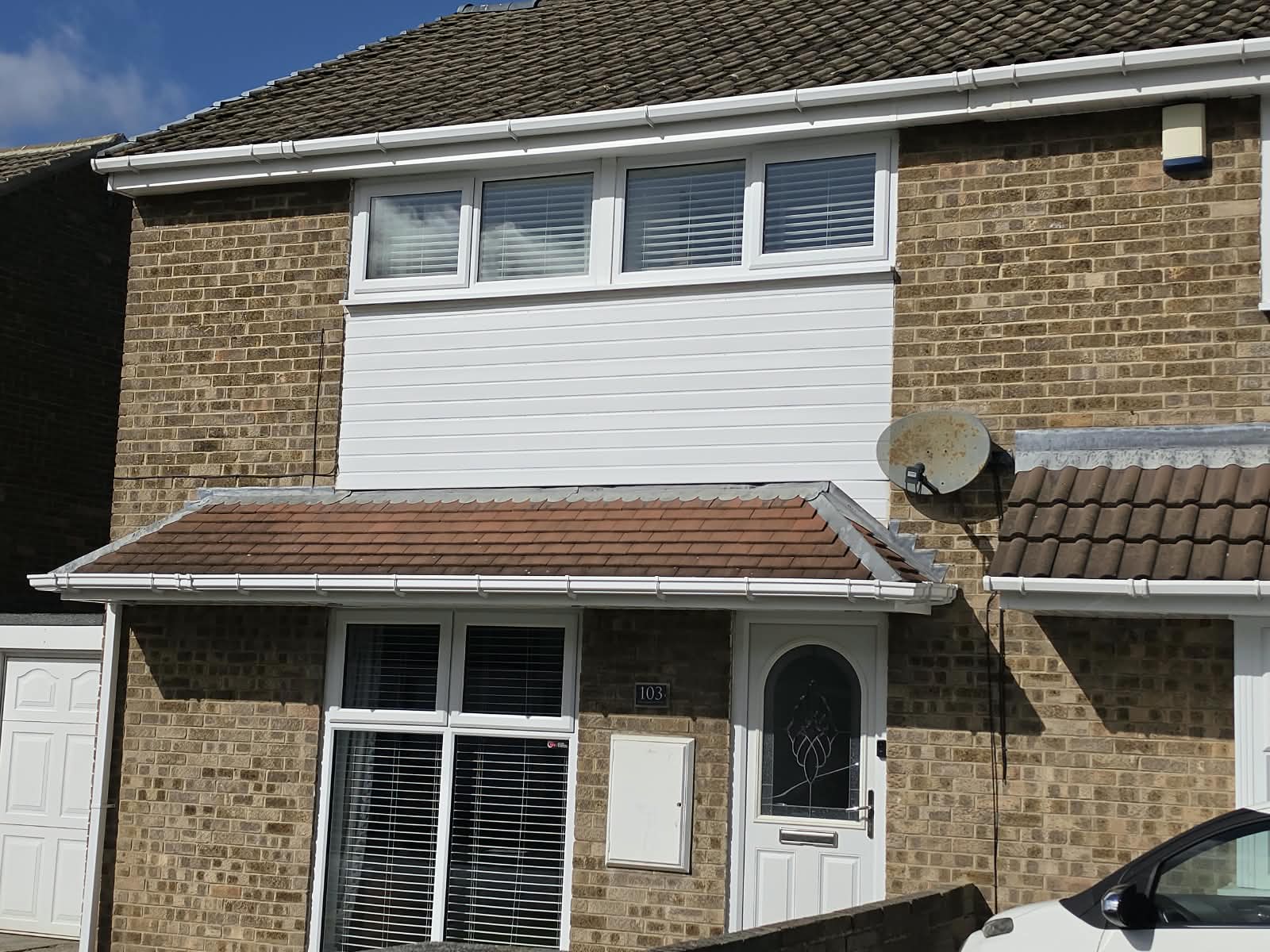 Brick house with white uPVC windows, a white front door, white cladding, fascia and guttering