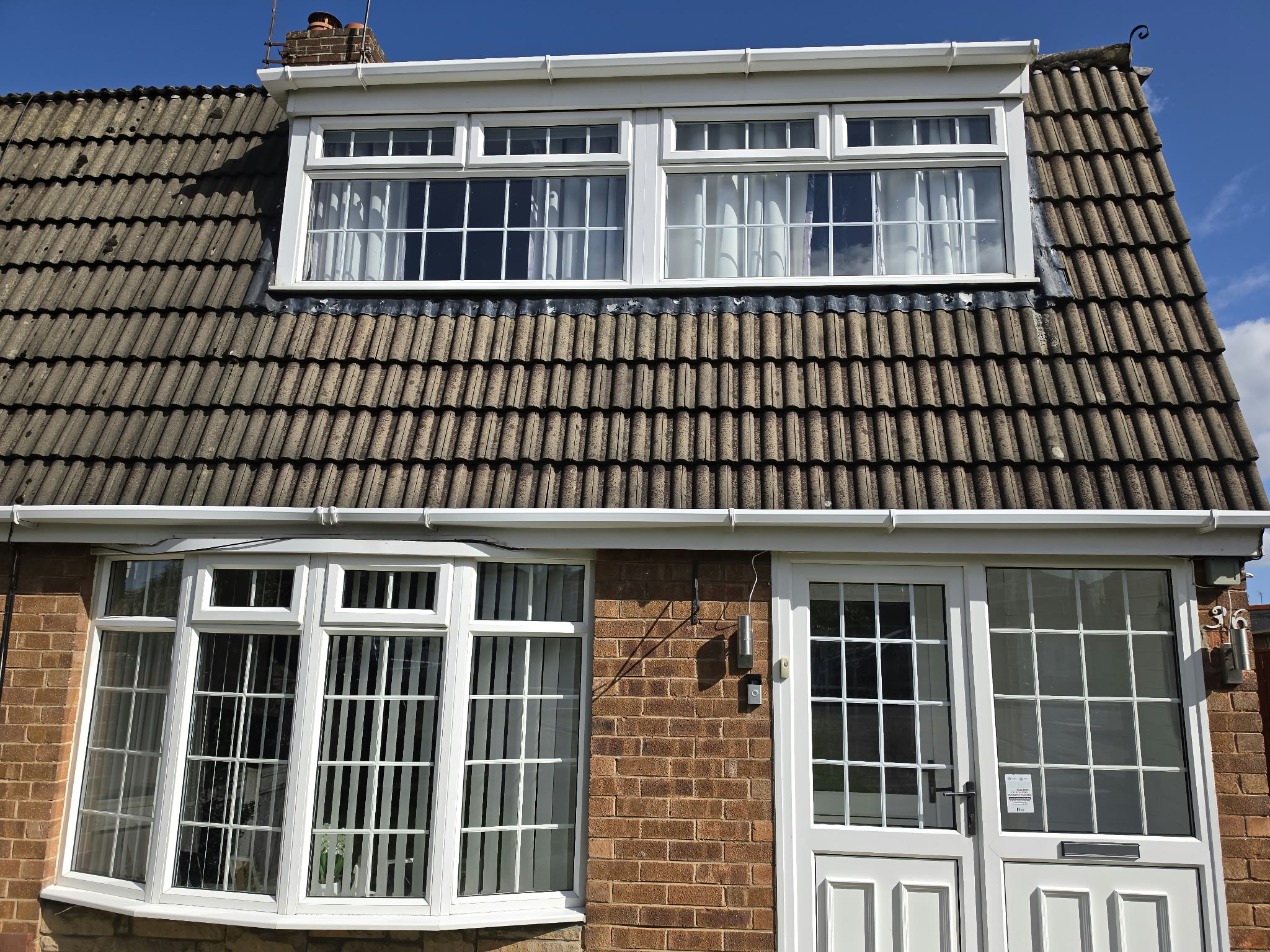 White uPVC bay window, dormer windows and a white front door, with fascia and guttering above